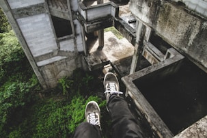 person sitting on gray abandoned building