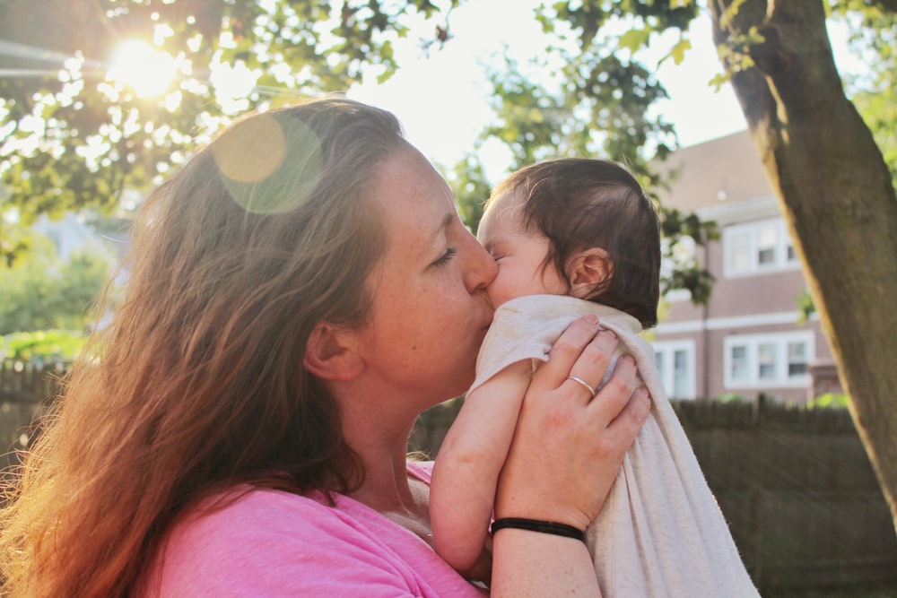 赤ん坊の頬にキスをする女性。