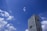 A modern high-rise building with numerous windows stands against a vibrant blue sky dotted with scattered white clouds.