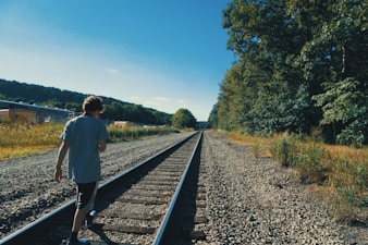 a man standing on a train track next to a forest
