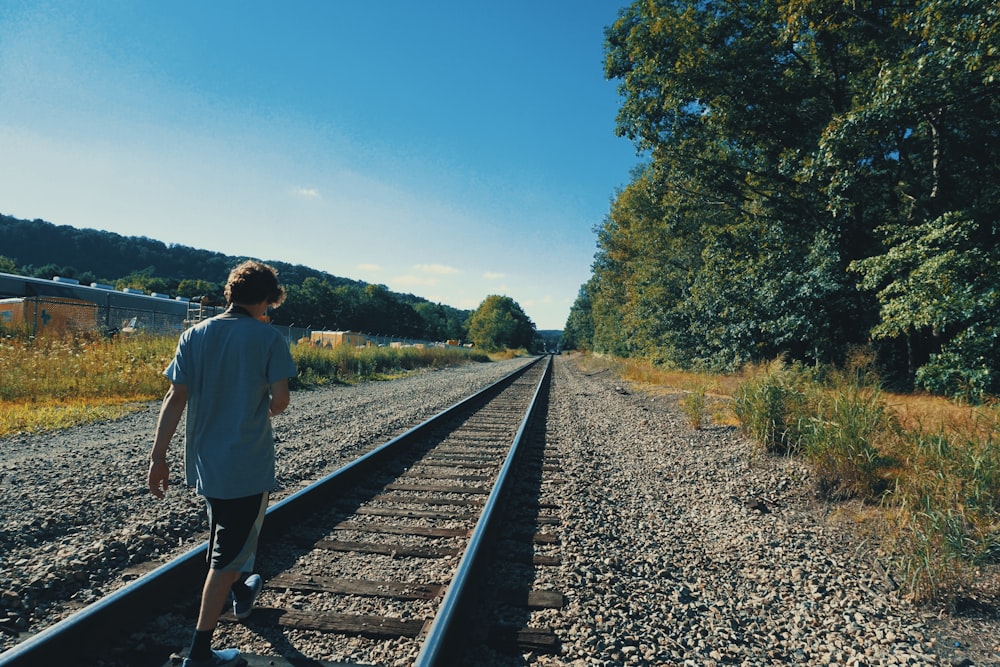 a man standing on a train track next to a forest