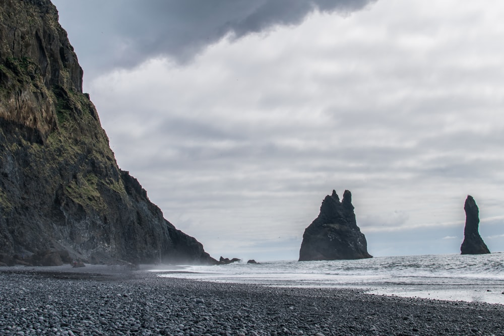 mountain near seashore under gray sky