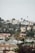A residential hillside community with a variety of houses surrounded by lush greenery and tall palm trees under an overcast sky.