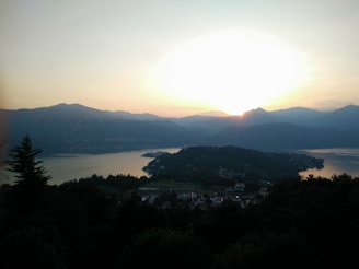 A serene landscape depicting a calm lake surrounded by mountains at sunrise.