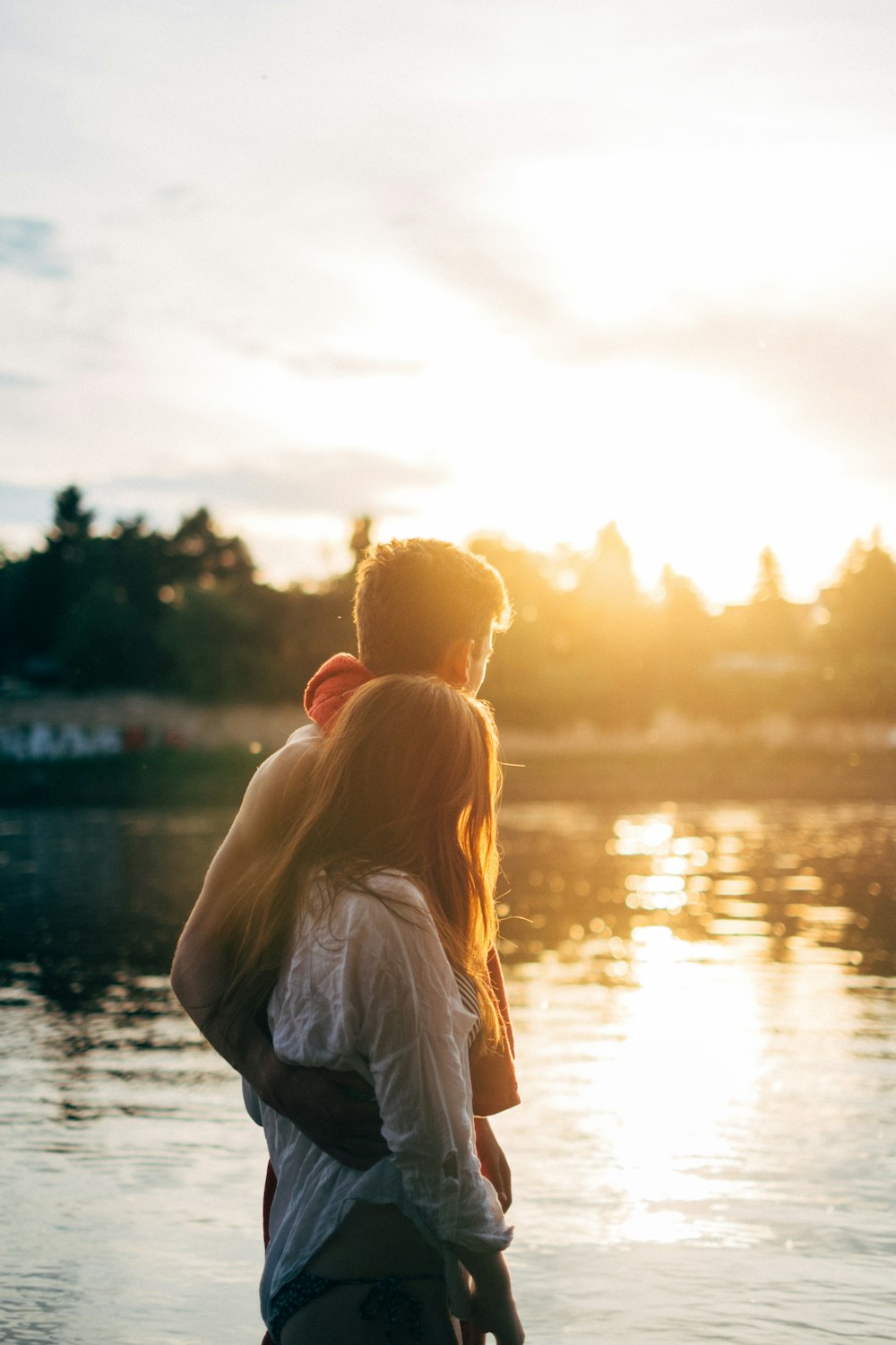 coppia che cammina sul lato del lago guardando la foto ravvicinata del tramonto