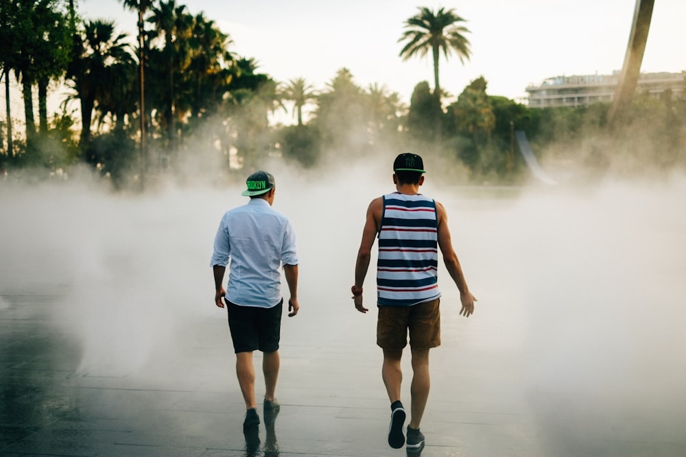 street photography of two men walking in front of water fountain