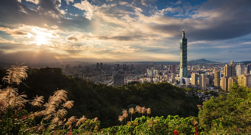 Taipei 101 rising above the city with mountains behind