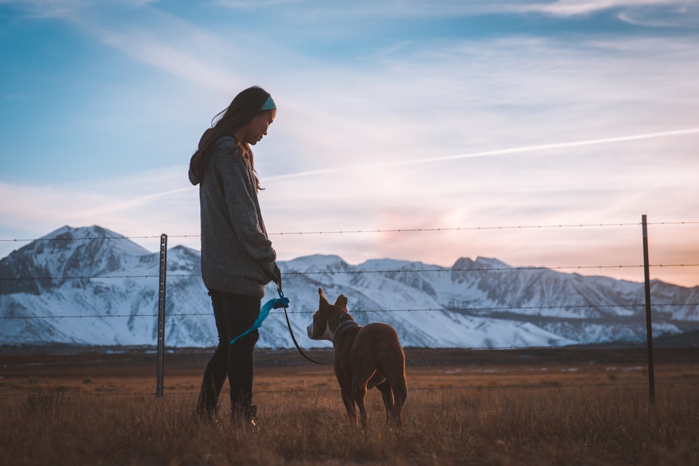 man holding dog leash on brown grass