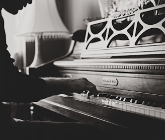 greyscale photo of man playing spinet piano close-up photo