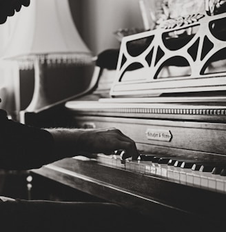 greyscale photo of man playing spinet piano close-up photo