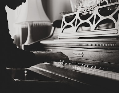 greyscale photo of man playing spinet piano close-up photo