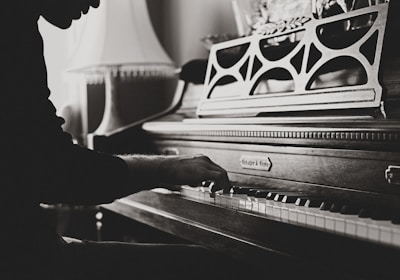 greyscale photo of man playing spinet piano close-up photo