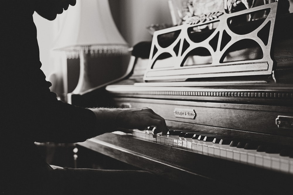 Graustufenfoto eines Mannes, der Spinett Klavier spielt Nahaufnahme
