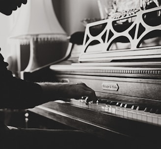 greyscale photo of man playing spinet piano close-up photo