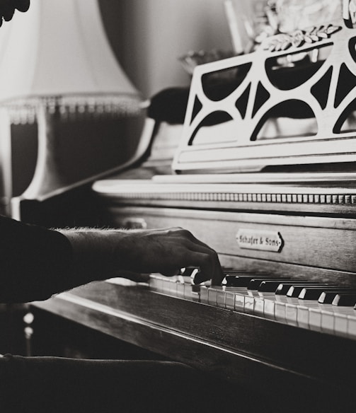 greyscale photo of man playing spinet piano close-up photo