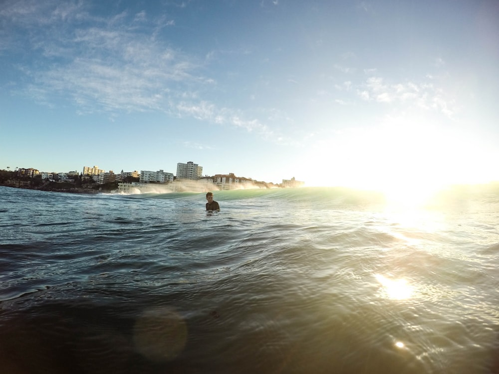 A boy standing at waist level in the ocean.