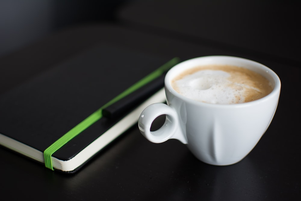 Weiße Tasse Kaffee auf schwarzer Oberfläche