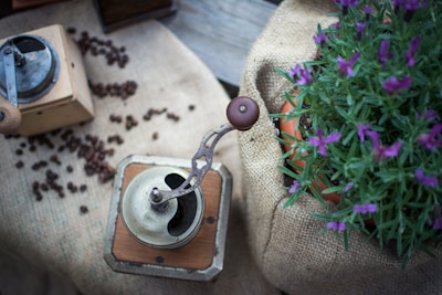 A vintage-style manual coffee grinder next to a steaming cup of black coffee.