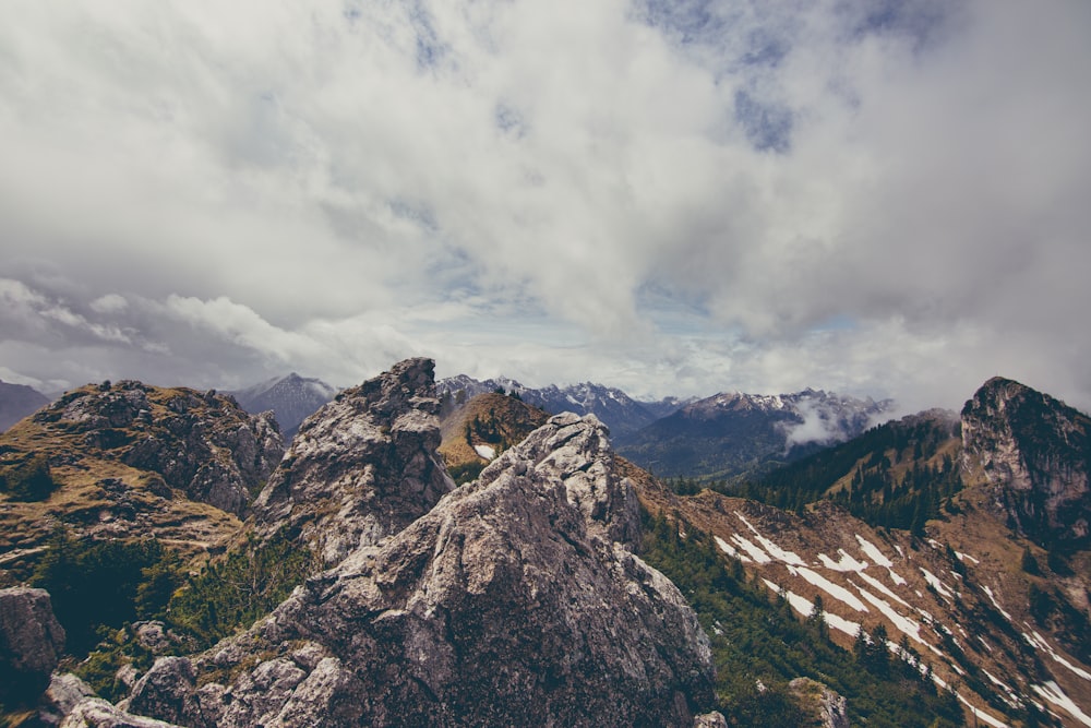 Montaña de roca marrón cubierta de árboles bajo un cielo blanco y nublado