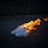 A pair of white sneakers is engulfed in flames against a dark background. The bright orange and yellow flames create a stark contrast with the shoes and the dimly lit setting.