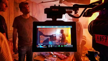 A director giving instructions on a busy film set in natural surroundings.