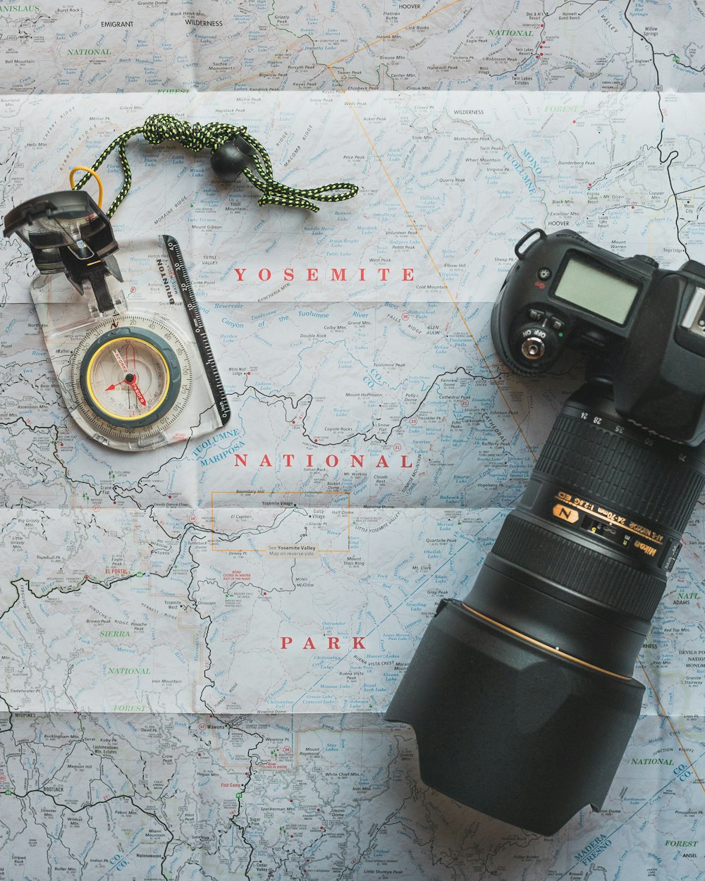 black Nikon DSLR camera beside of map compass