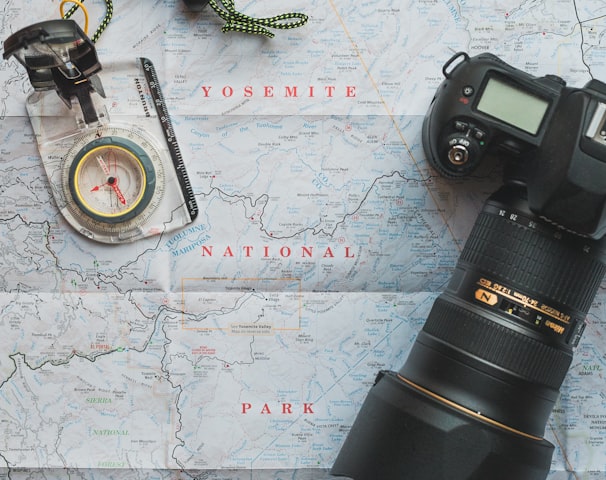 black Nikon DSLR camera beside of map compass