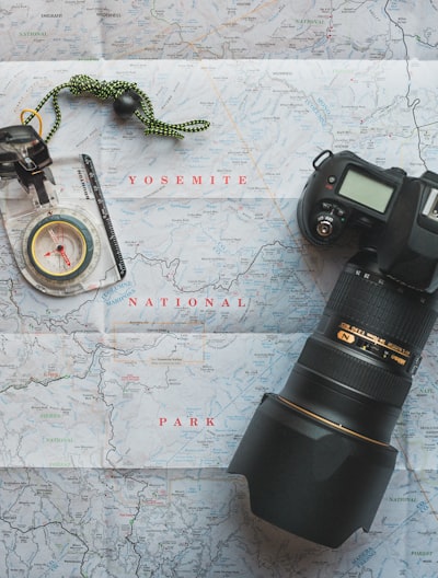 black Nikon DSLR camera beside of map compass