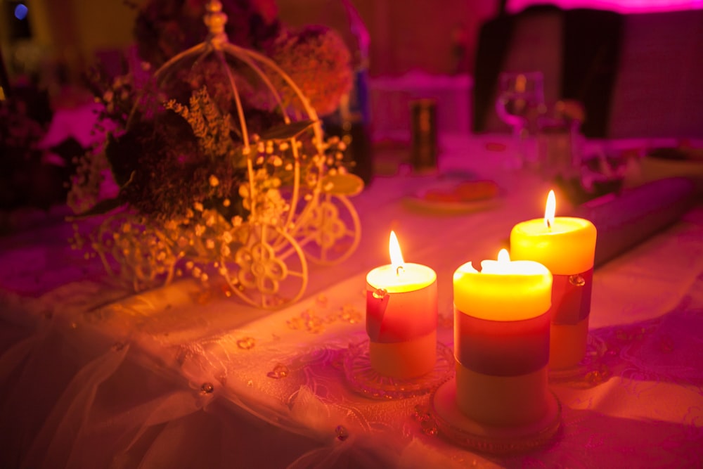 Three lit candles on a table at a princess themed party.
