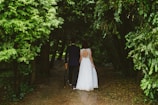 couple walking under green trees