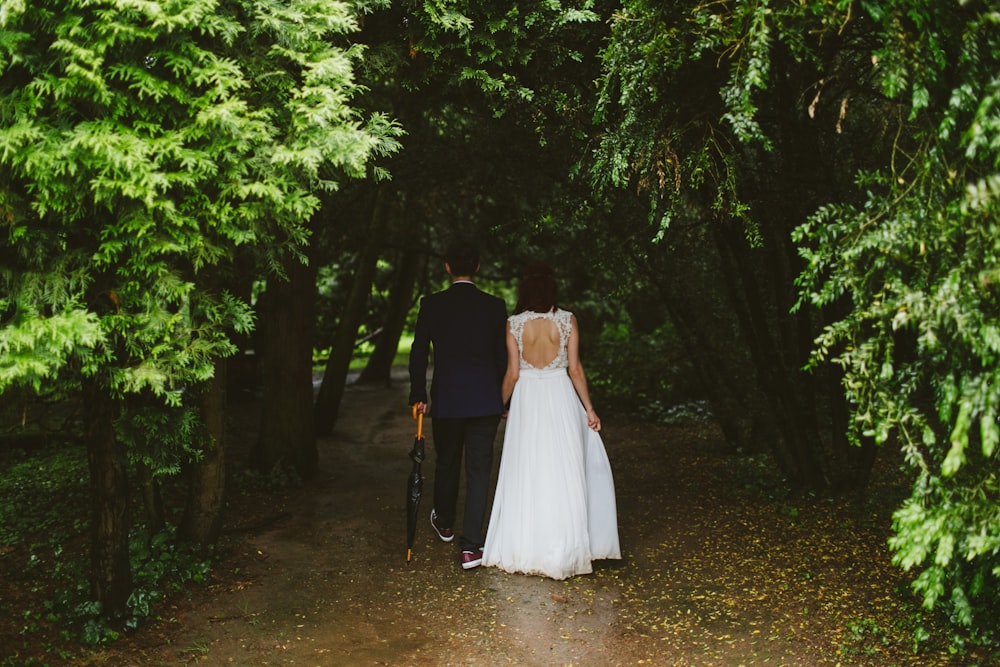 couple walking under green trees