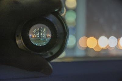 A close-up of a camera lens capturing a vibrant urban landscape at golden hour.