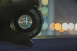 A filmmaker adjusting a camera lens with a vibrant cityscape in the background.