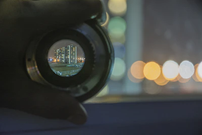 A vibrant behind-the-scenes shot of a filmmaker adjusting a camera lens with a glowing cityscape in the background.