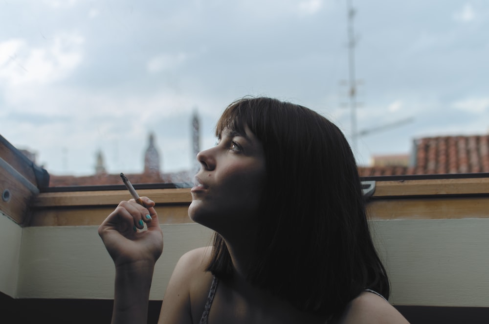 낮 시간 동안 막대기 담배를 들고 있는 여자