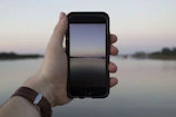 Hands holding a phone showing a calm, nature-themed game interface in soft colors.