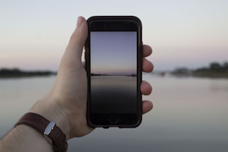 Hands holding a smartphone showing a calming nature scene on the screen.