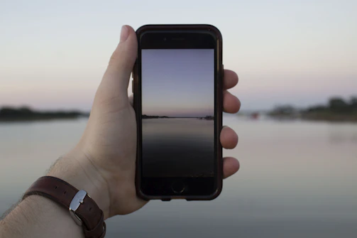 A smiling teenager holding a smartphone with a peaceful background symbolizing faith and calm.