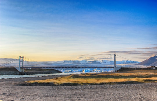 photo of gray concrete bridge under blue sky at daytime in Jökulsárlón Iceland