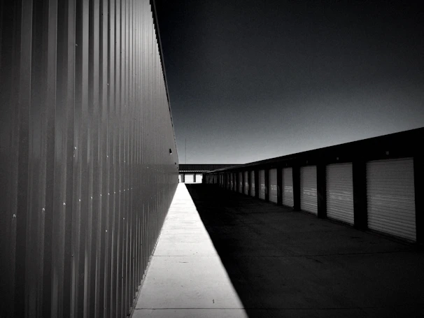 A well-lit, secure storage facility with rows of locked units and visible CCTV cameras at dusk.