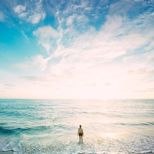 woman on sea in front of sun