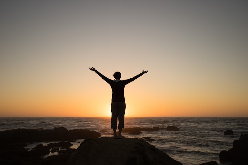 Silhouette of a person with arms raised at sunset