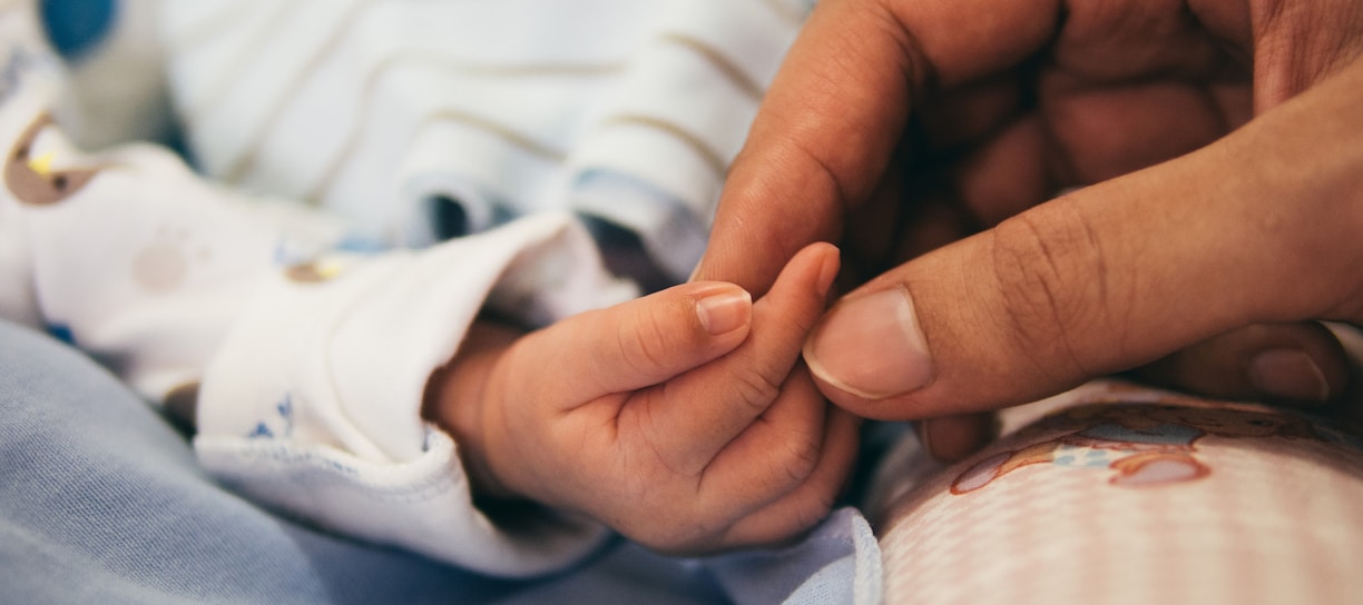 person holding baby's index finger