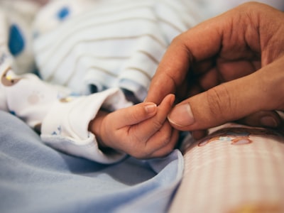 person holding baby's index finger birth teams background