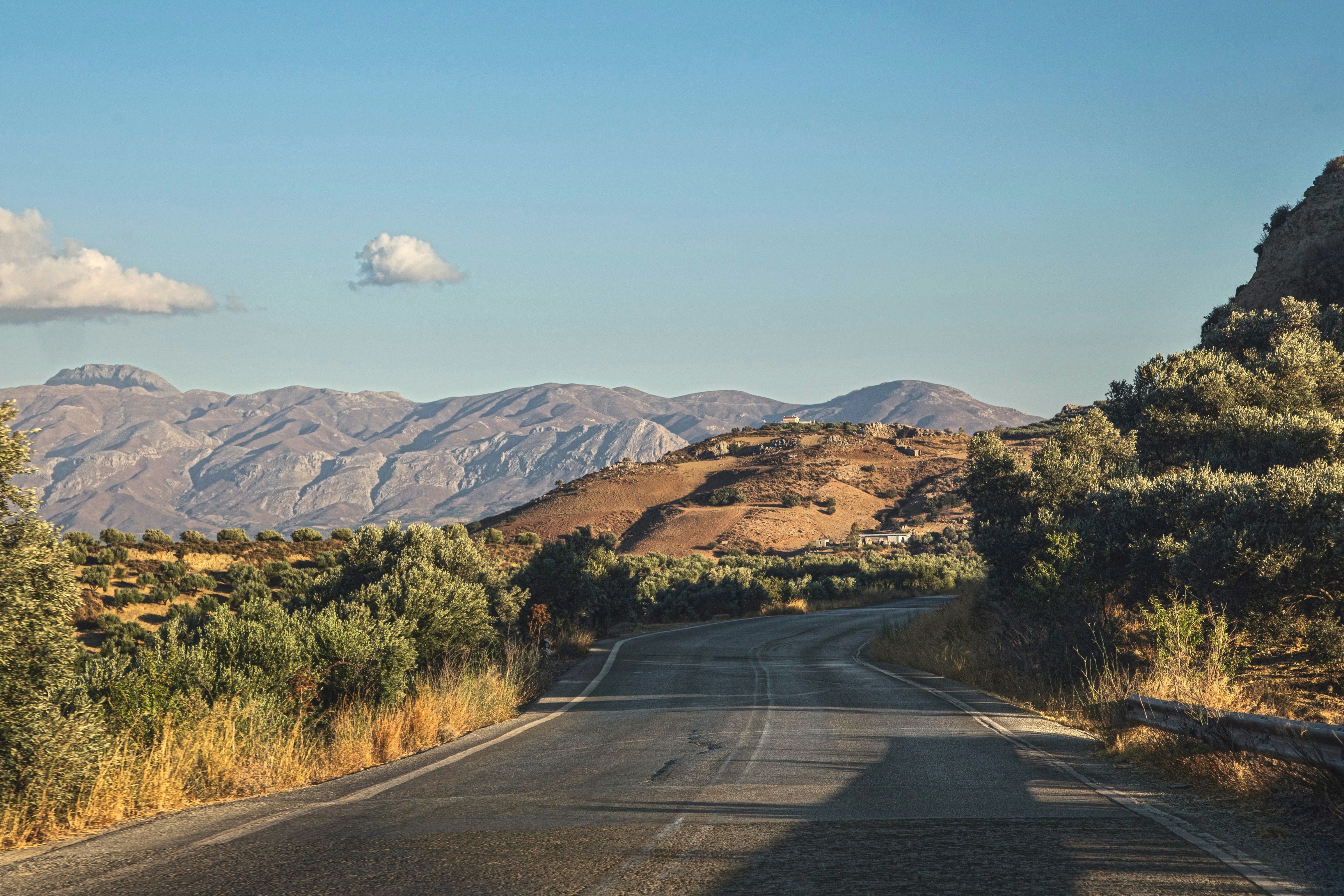 gray asphalt road near green grass field and mountains during daytime