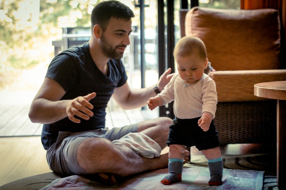 A man helping teach his 1 year old how to walk.