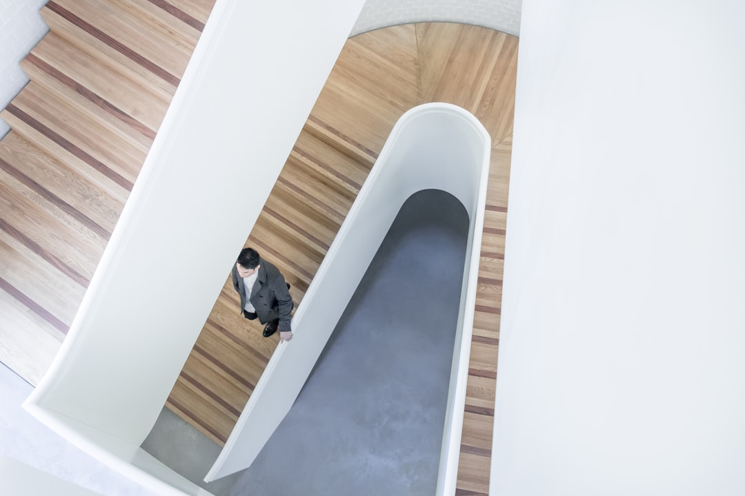 person stepping down on brown wooden stairs aerial photography, Man on a wooden staircase