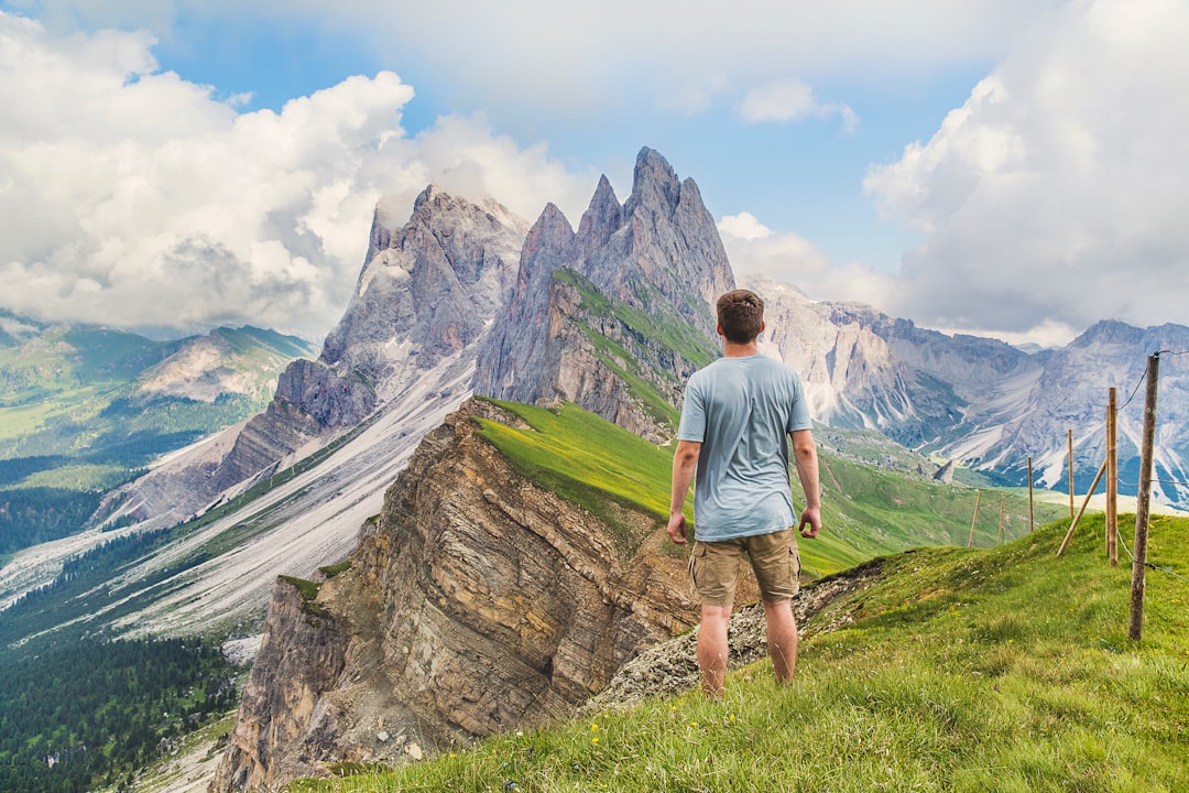 man in blue T-shirt on top of the mountain under the blue sky