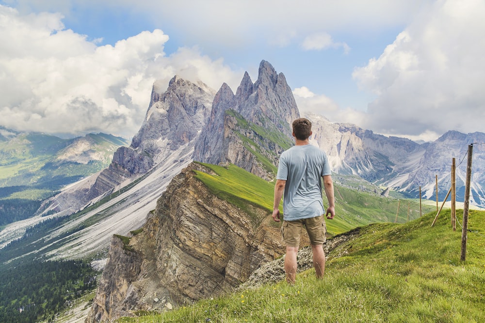 man in blue T-shirt on top of the mountain under the blue sky