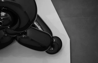 Minimalist sculptural piece with smooth curves and a matte white finish displayed on a pedestal.
